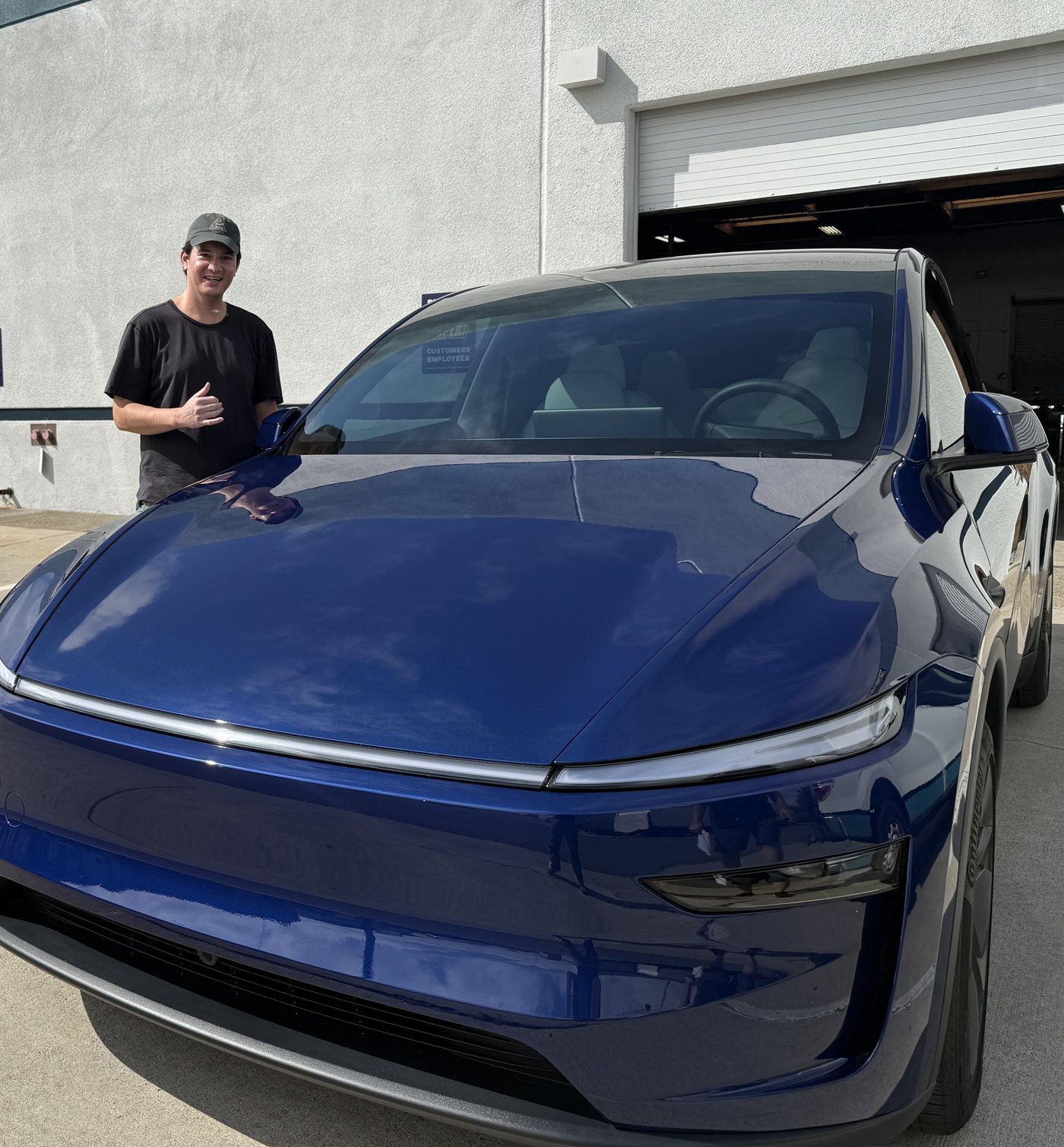 Scott smiling and throwing a shaka beside a dark blue SUV